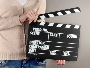 Film üretim clapper panosundaki gri arka plan üzerinde eller