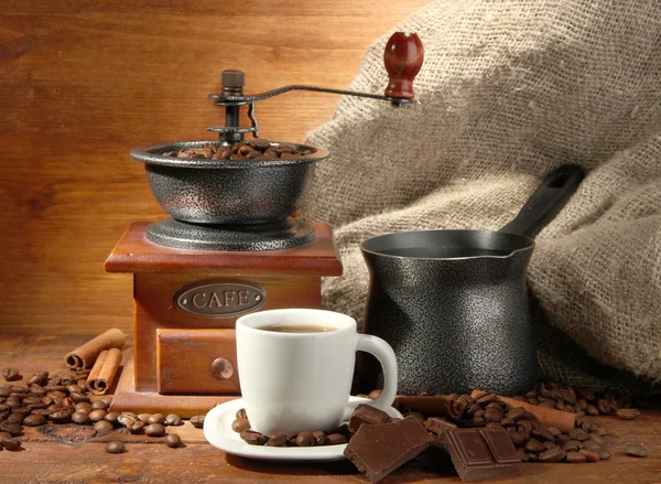 Coffee grinder, turk and cup of coffee on brown wooden background — Stock Photo, Image