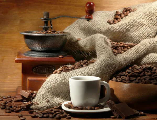 Coffee grinder and cup of coffee on brown wooden background — Stock Photo, Image