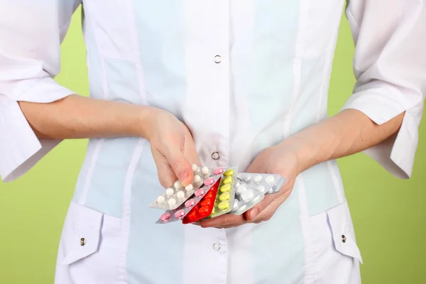 Close-up of female doctor hand holding pills, on color background — Stock Photo, Image