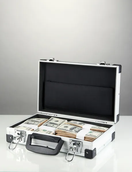 Suitcase with 100 dollar bills on grey background — Stock Photo, Image