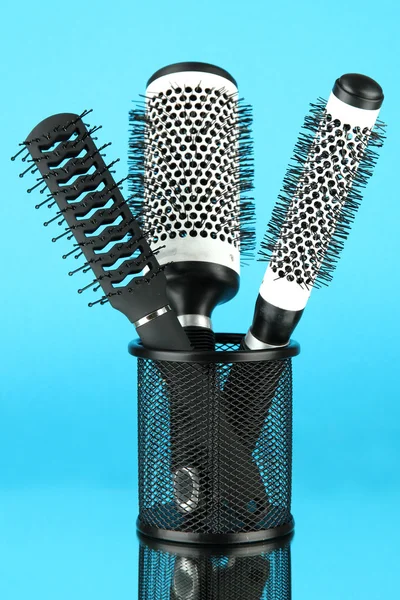 Iron basket with round hair brushes, on color background — Stock Photo, Image