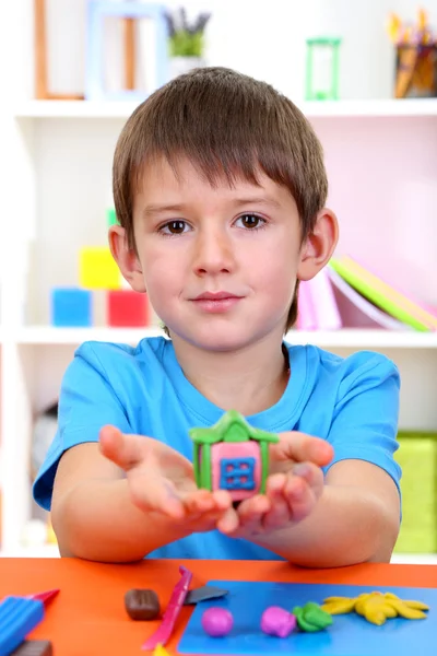 Cute little boy holding hand-made plasticine hourse over desk — Stock Photo, Image