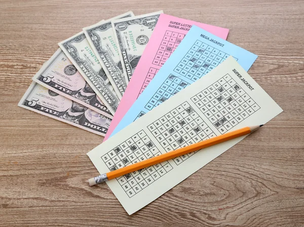 Лотерейные билеты с карандашом и деньгами, на деревянном фоне — стоковое фото
