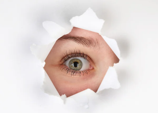 紙のシートに穴を通して見る女性の目 — ストック写真