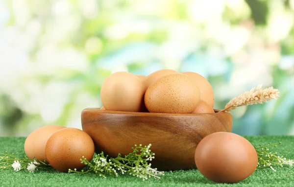 Eggs in bowl on grass on natural background — Stock Photo, Image