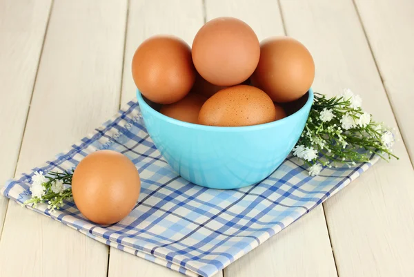 Eggs in blue bowl on wooden table close-up — Stock Photo, Image