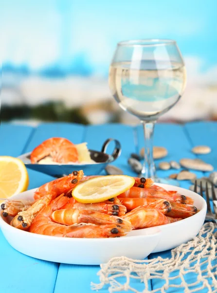 Camarones con limón en plato sobre mesa de madera sobre fondo azul natural —  Fotos de Stock