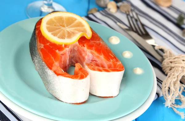 Stück roter Fisch auf Teller mit Gewürzen und Soße auf Holztisch in Großaufnahme — Stockfoto