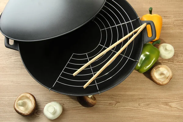 Black wok pan and vegetables on kitchen table, close up — Stock Photo, Image