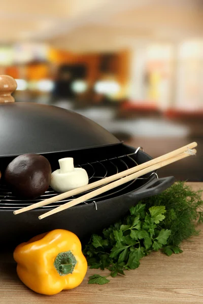 Černý pánev wok a zeleniny na kuchyňský dřevěný stůl, zblízka — Stock fotografie