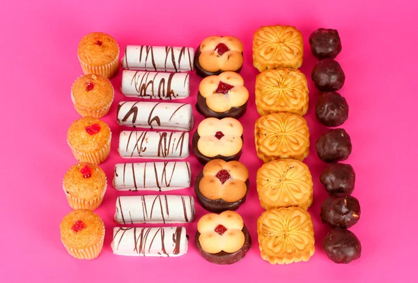 Édes sütemények, rózsaszín háttér — Stock Fotó