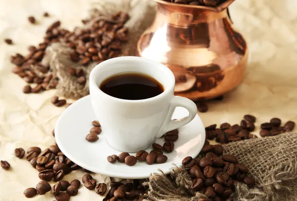 Cup and pot of coffee on beige background — Stock Photo, Image