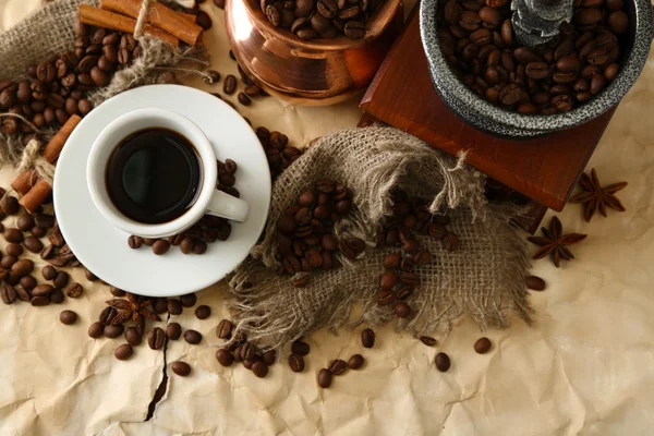 Cup of coffee, pot and grinder on beige background — Stock Photo, Image