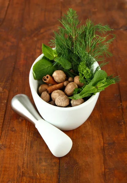 Herbs and spices in ceramic mortar, on wooden background — Stock Photo, Image