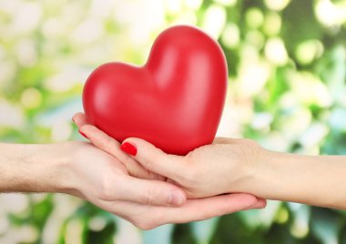 kadın ve adam ellerini, yeşil zemin üzerine kırmızı kalp