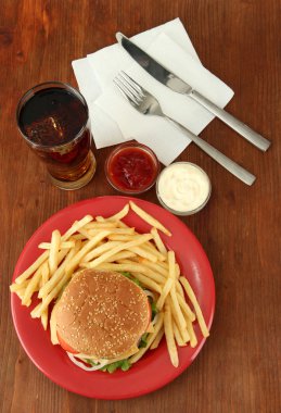 patates kızartması ve ahşap zemin üzerinde soğuk içecek ile lezzetli peynirli burger