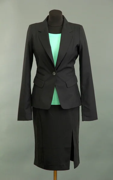 Бирюзовая блузка и черная юбка с пальто на манекене на сером фоне — стоковое фото