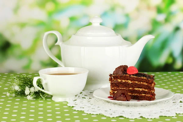 Teapot, cup of tea and delicious cake on natural background — Stock Photo, Image