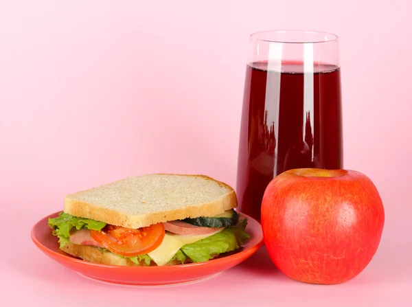Sandwich på plattan med äpple och juice på rosa bakgrund — Stockfoto