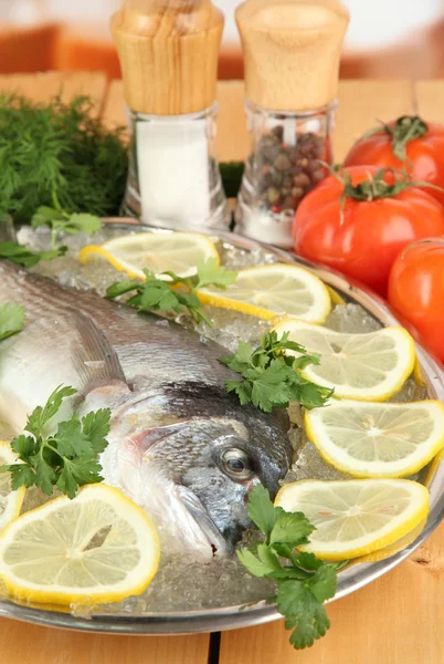 Pescado fresco de dorado en bandeja con limón y perejil sobre mesa de madera —  Fotos de Stock