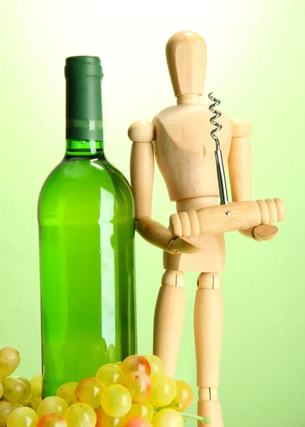 Маннекін з пробкою та пляшкою вина на зеленому фоні — стокове фото