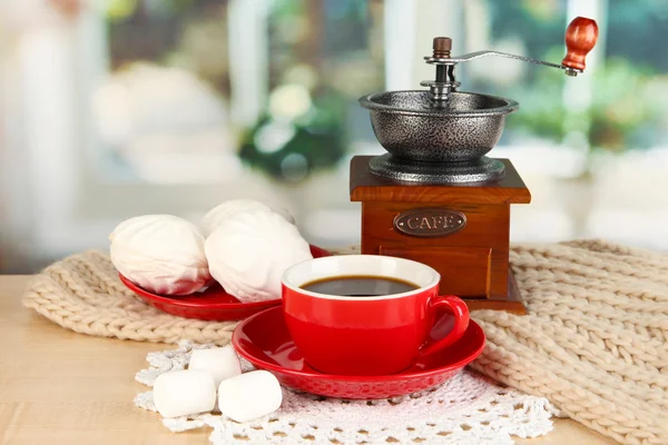 Чашка кофе с шарфом и кофе мельница на столе в номере — стоковое фото