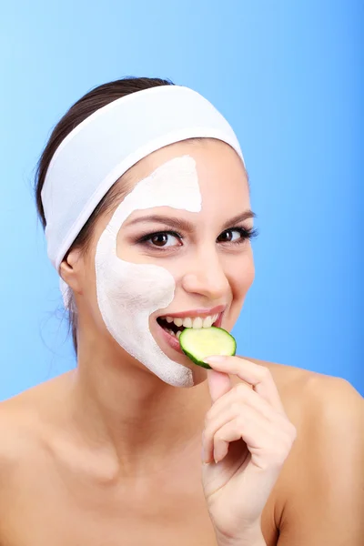 Mujer joven con máscara facial de arcilla, sobre fondo azul —  Fotos de Stock