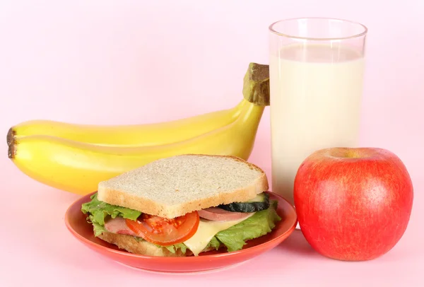 Sandwich auf Teller mit Obst und Milch auf rosa Hintergrund — Stockfoto