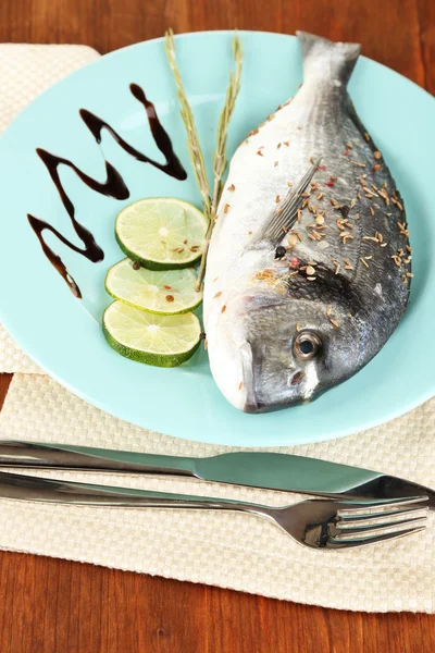 Fish dorado with lemon on plate on wooden table close-up — Stock Photo, Image