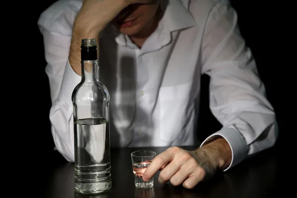 Homem com garrafa de álcool, sobre fundo preto — Fotografia de Stock