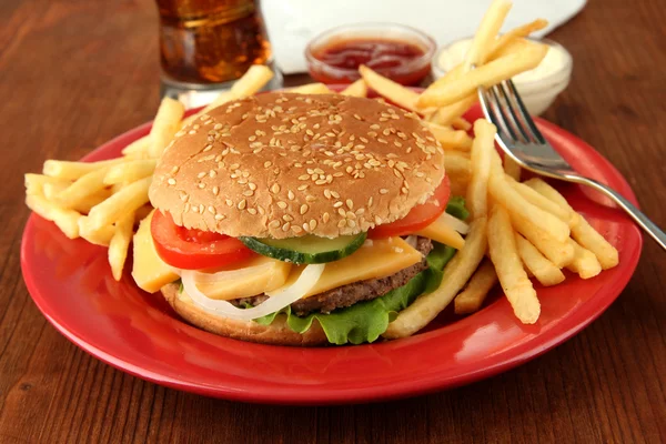 Sabrosa hamburguesa con patatas fritas y bebida fría, sobre fondo de madera —  Fotos de Stock