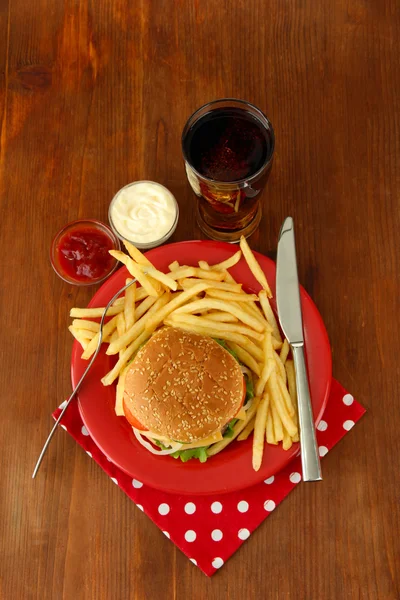 patates kızartması ve ahşap zemin üzerinde soğuk içecek ile lezzetli peynirli burger