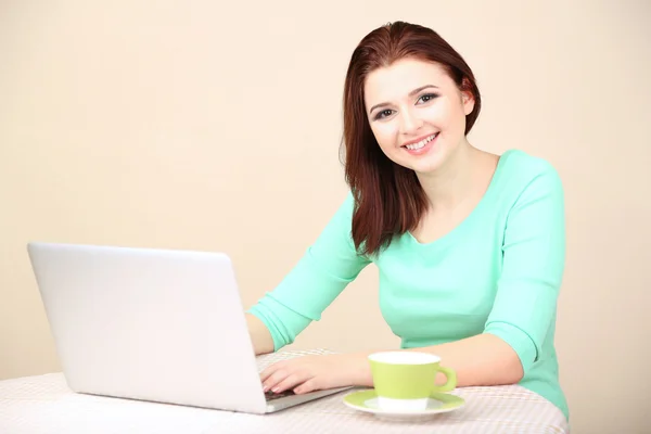 Mooie jonge vrouw die op laptop op lichte achtergrond werkt — Stockfoto