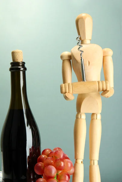 Manequim com saca-rolhas e garrafa de vinho, sobre fundo cinza — Fotografia de Stock
