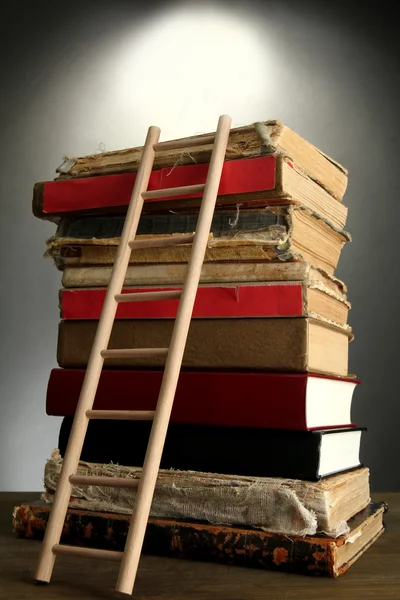 Eski kitaplar ve Ahşap merdiven, gri arka plan üzerine — Stok fotoğraf