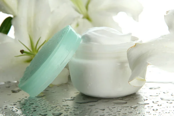 Crema cosmética y hermoso lirio, de cerca — Foto de Stock