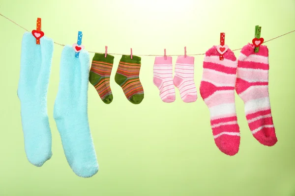 Colorful socks hanging on clothesline, on color background — Stock Photo, Image