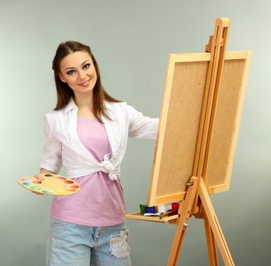 güzel bir genç kadın ressam gri arka plan üzerinde iş başında