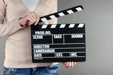 Film üretim clapper panosundaki gri arka plan üzerinde eller