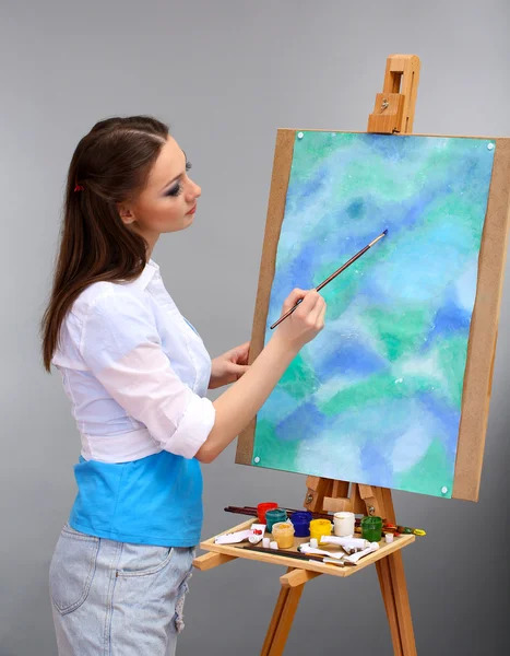 Beautiful young woman painter at work, on grey background — Stock Photo, Image