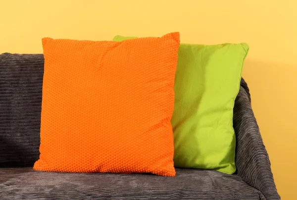 Colorful pillows on couch on yellow background — Stock Photo, Image