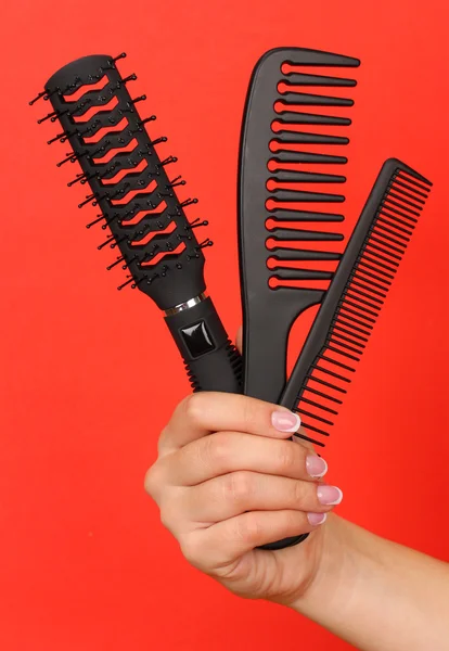 Three combs in female hand on color background — Stock Photo, Image