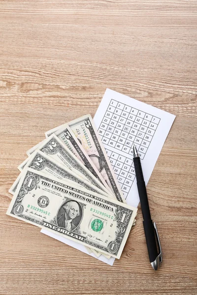 Lottery tickets with pen and money, on wooden background — Stock Photo, Image