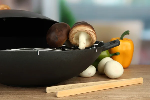 Black wok pan and vegetables on kitchen table, close up — Stock Photo, Image