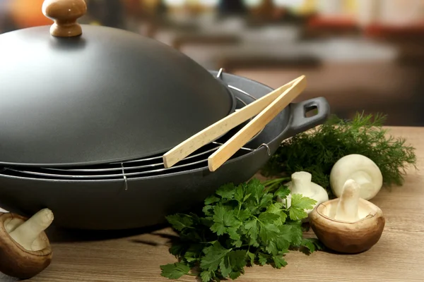 Black wok pan and mushrooms on kitchen wooden table, close up — Stock Photo, Image