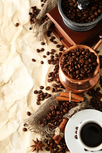 Cup of coffee, pot and grinder on beige background