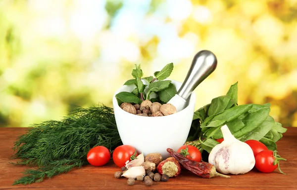 Komposition aus Mörser, Gewürzen, Tomaten und grünen Kräutern, auf hellem Hintergrund — Stockfoto