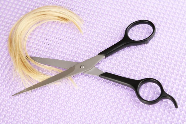 Pieces of hair cut with scissors on purple background — Stock Photo, Image