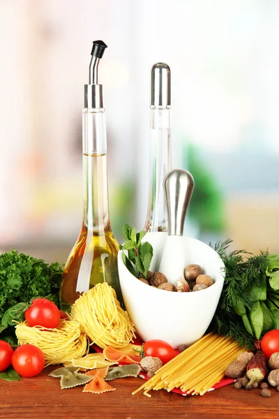 Composition of mortar, pasta and green herbals, on bright background — Stock Photo, Image